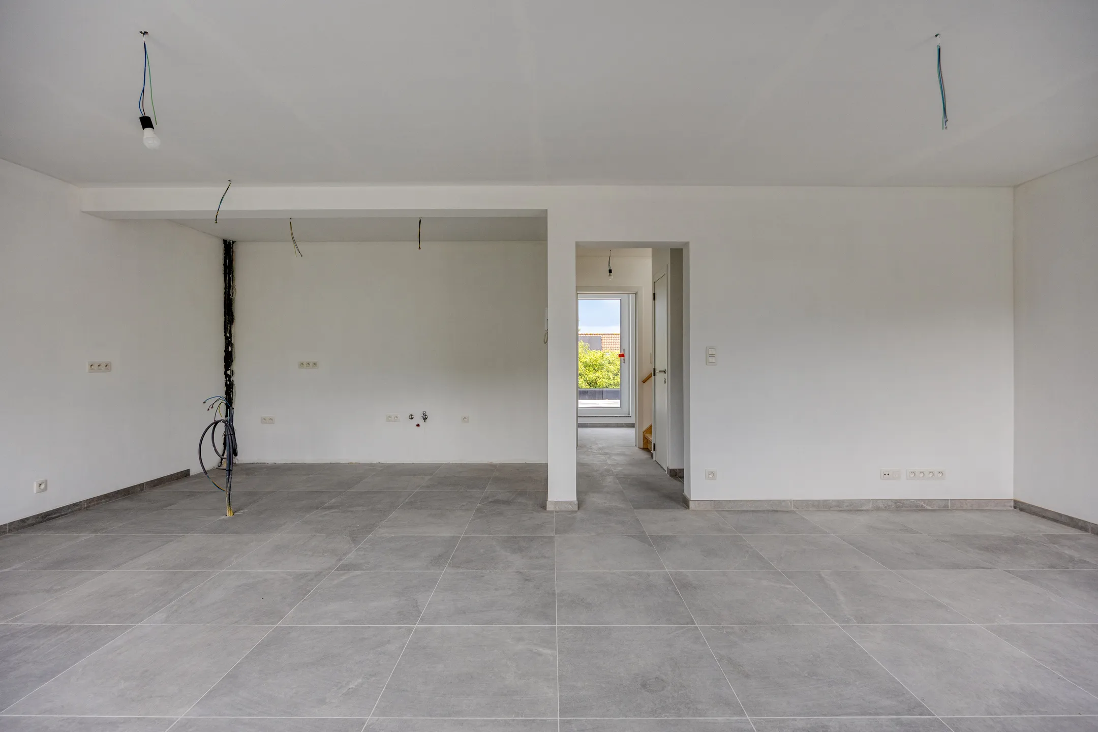 Open leef- en keukenruimte met zicht op gang en terrasdeur