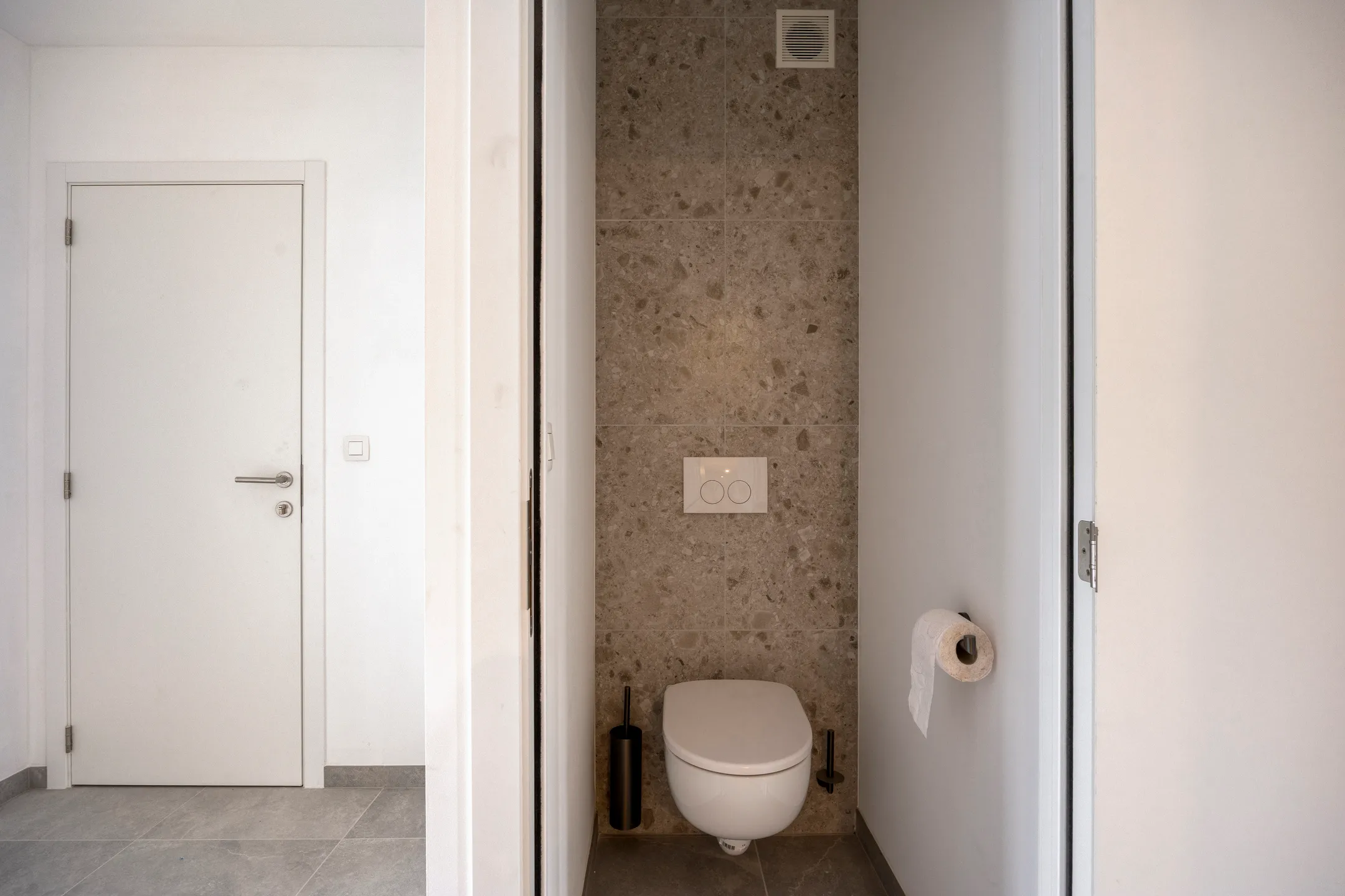 Gastentoilet met natuursteentegels en hangtoilet