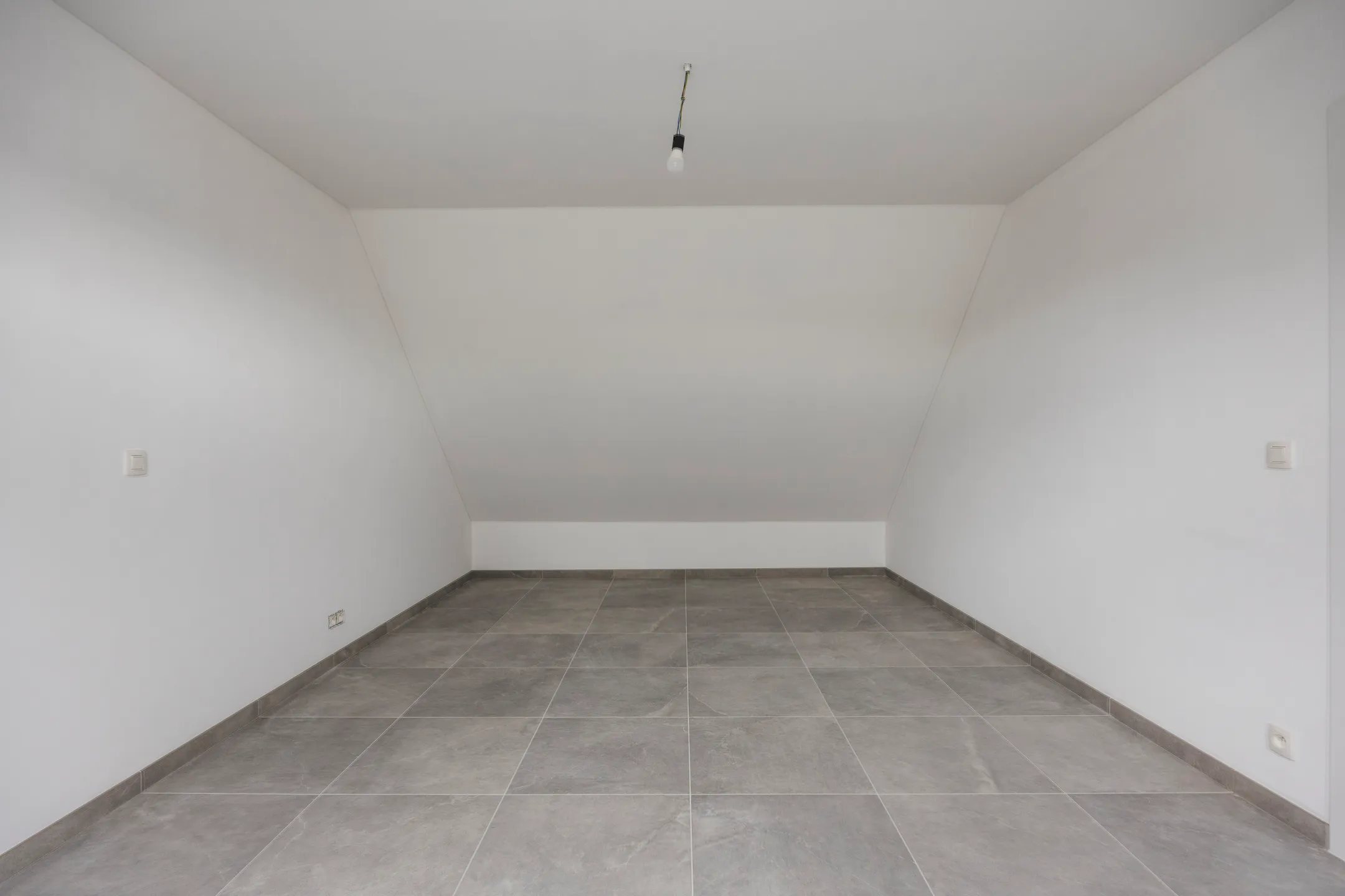 Zolderkamer met schuine wanden en tegelvloer