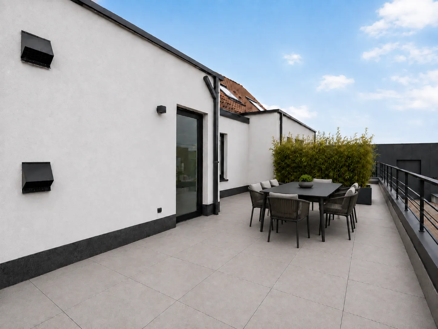 Impressie van het dakterras met eettafel langs de gevel